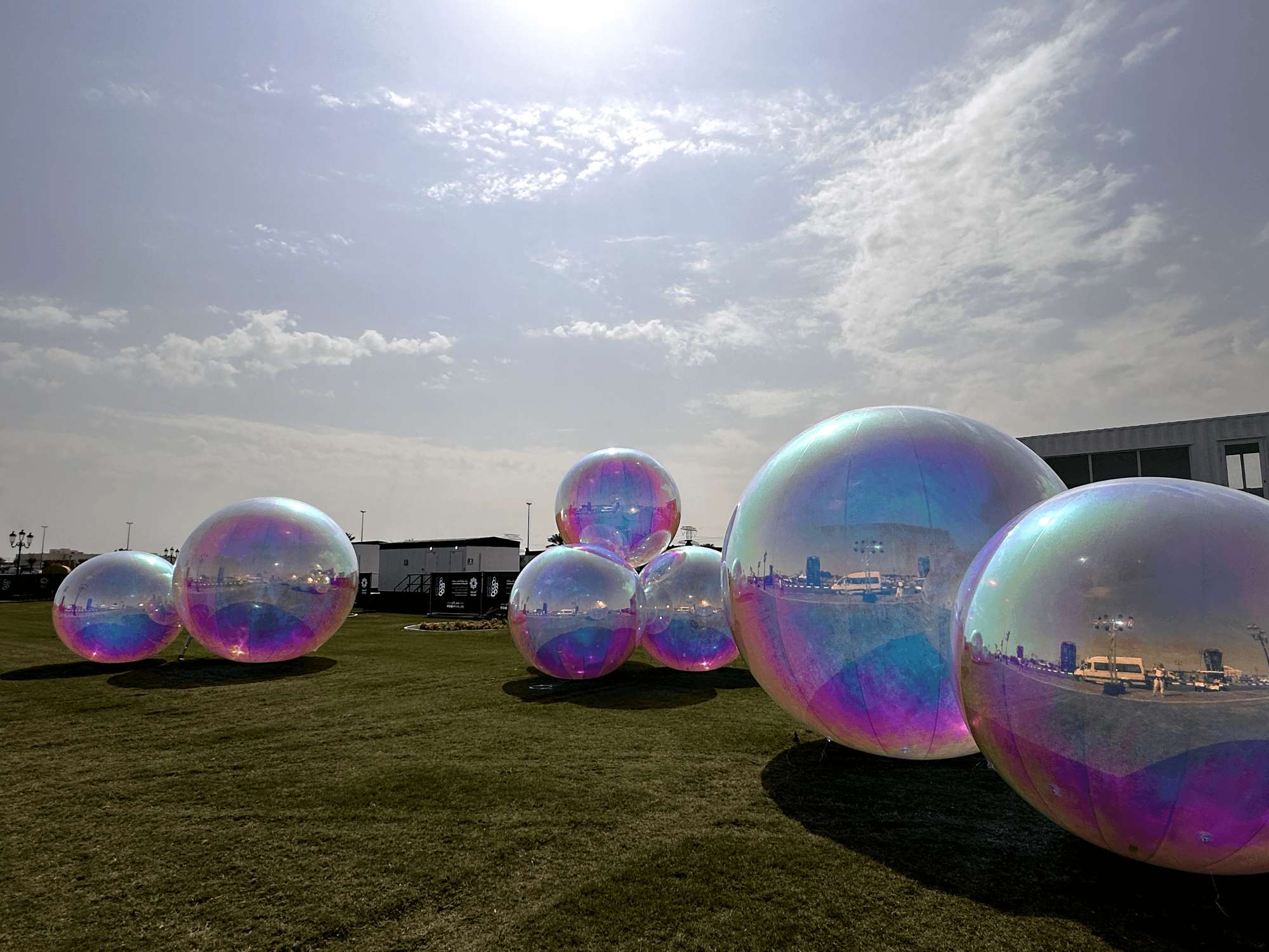 Iridescent giant bubbles on a lawn under a blue sky