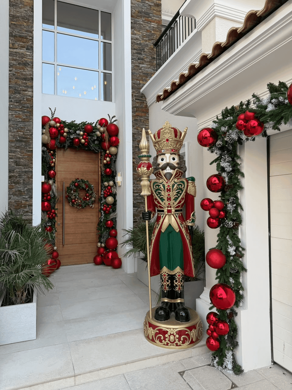 Entrance with garlands around the door, a wreath and a life-size nutcracker, decorated by Pampa