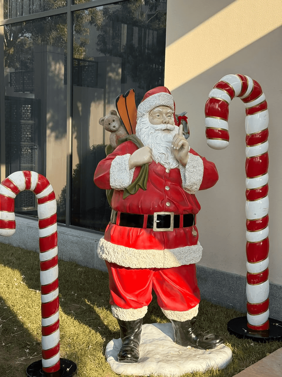 Santa Claus figure between giant candy canes in a garden
