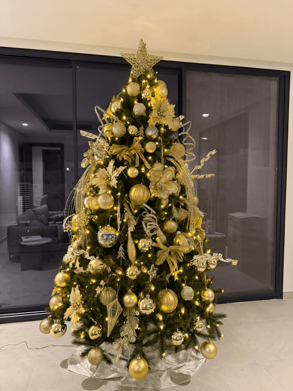 A tall Christmas tree decorated in gold ornaments, styled and installed by Pampa