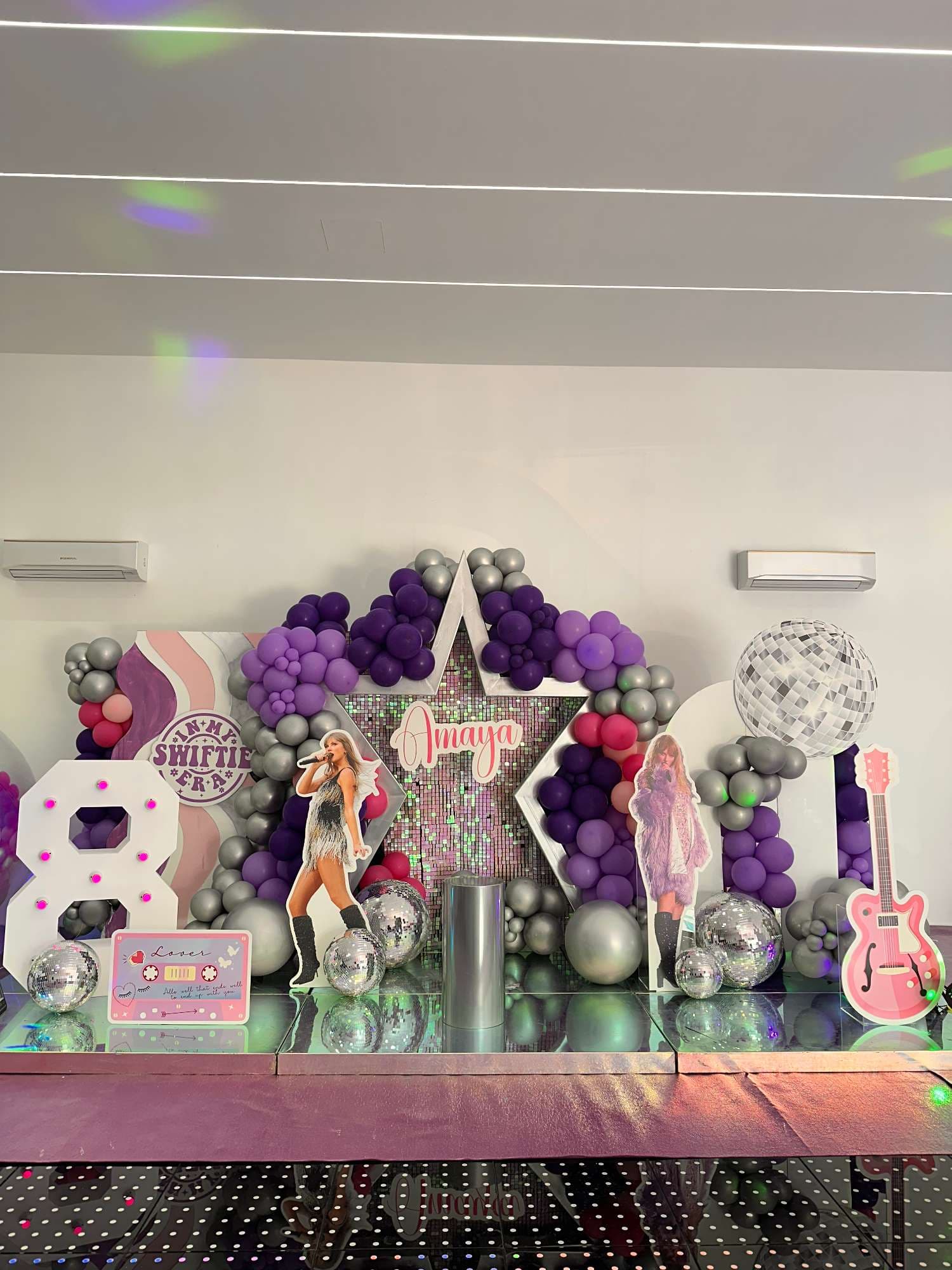 Purple, pink and silver balloon backdrop with a personalised star and music-themed birthday props at Pampa