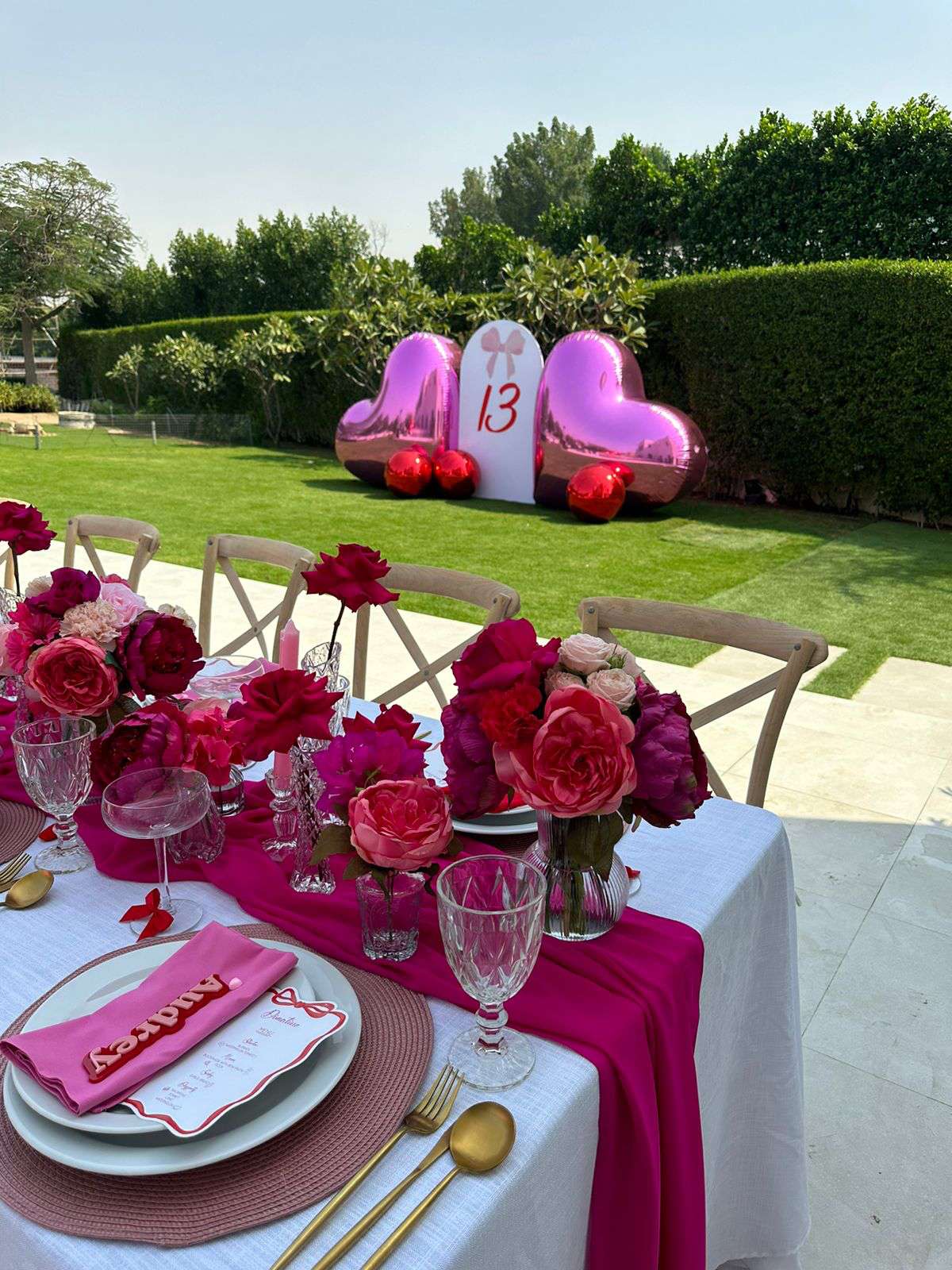 Outdoor dinner table with pink flowers and place settings in a garden